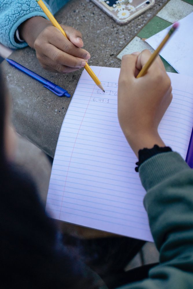 Close-up shot of two people writing on ruled paper