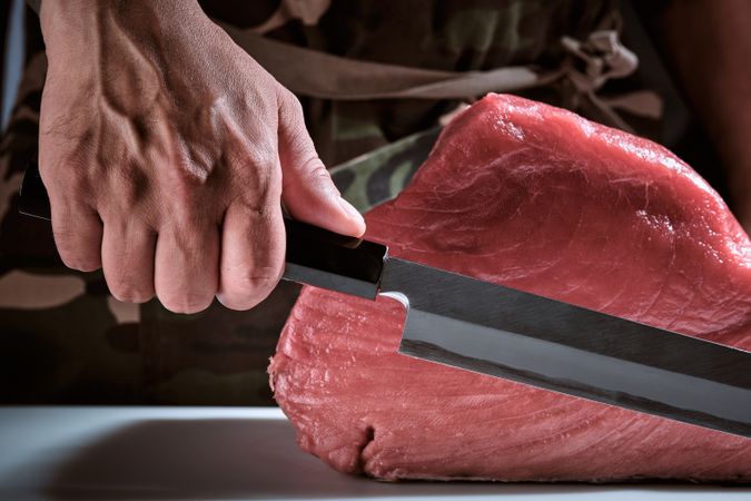 Male hands of a chef cutting a delicious loin of fresh bluefin t