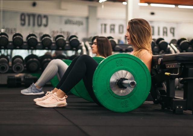 two young fitness women training hip thrust in a gym