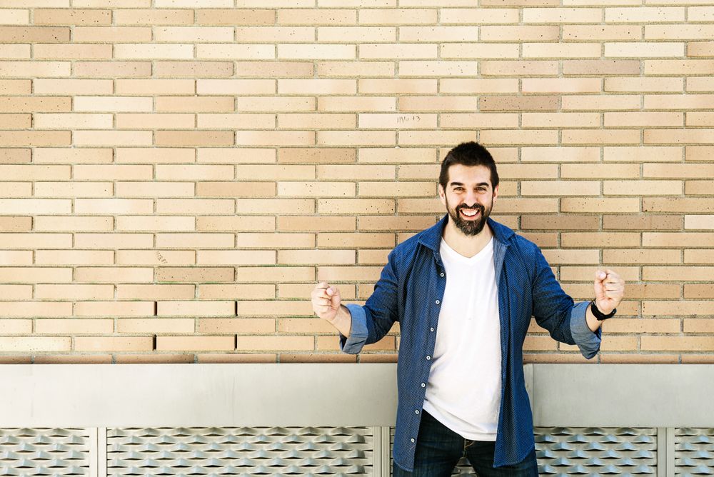 Man celebrating a win in front of brick wall