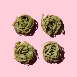 Green bird's nest pasta organized over pink background