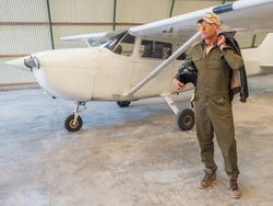 Confident pilot beside retro plane in hangar