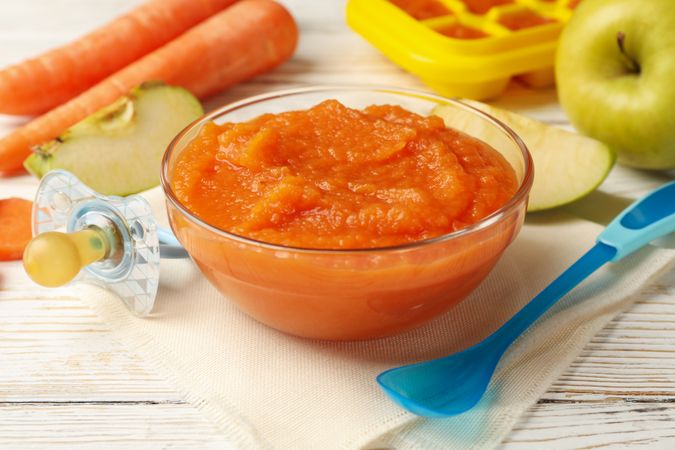 Composition with baby food on plain wooden background