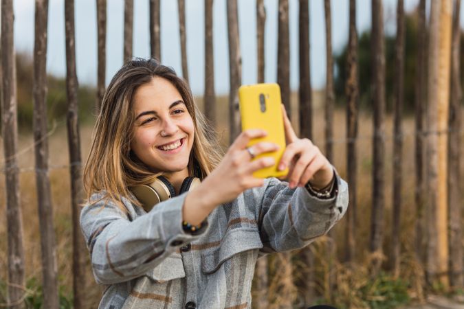 Young woman taking selfie on smartphone witting on wooden path