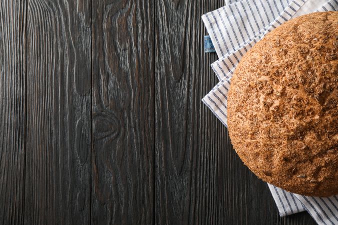 Bread on kitchen towel on wooden background, space for text and top view