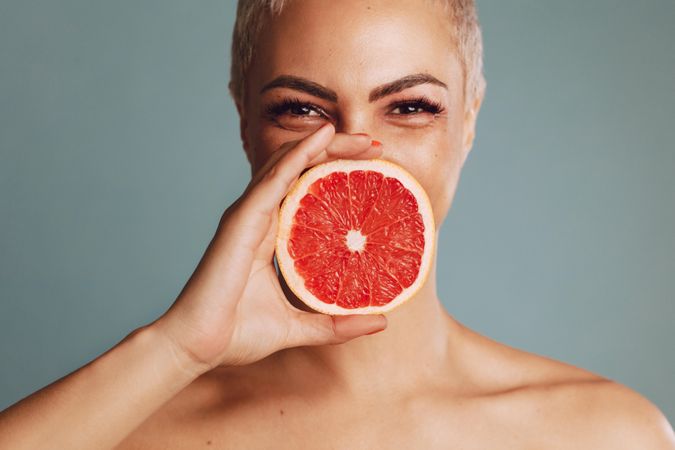 Beautiful female model holding a grapefruit slice