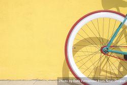 Wheel of bike outside on bright yellow wall 0Pp9a0