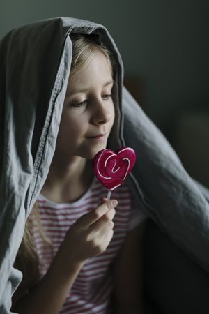 Profile view of young girl with a pink lollipop