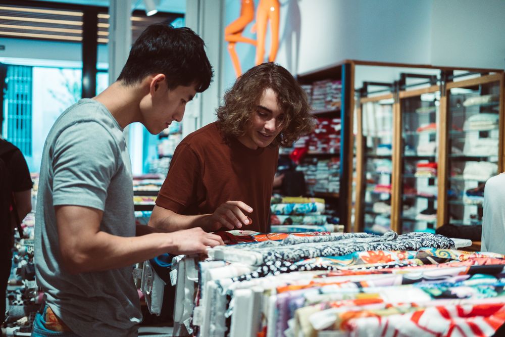 Captivated multiracial men looking for fabric in drapery store