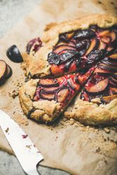 Fruit tart on parchment paper with knife, close up
