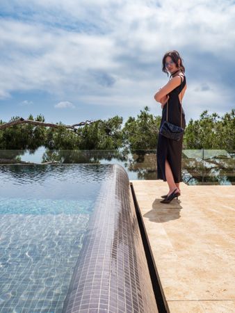 Woman in a dress elegantly poses near the pool at a luxurious villa
