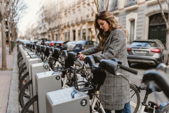 Woman choosing rental bicycle on parking lot