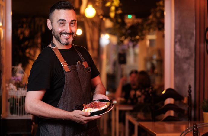 Cheerful waiter serving snack in restaurant