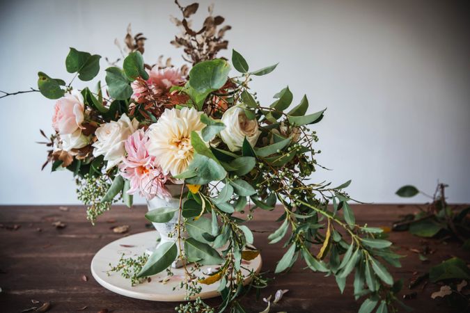Composition of flowers and plants in vintage vase on board