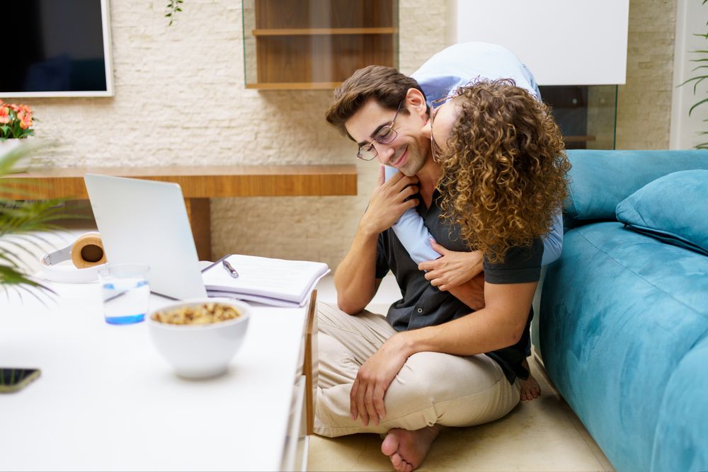 Affectionate couple working from home together in living room