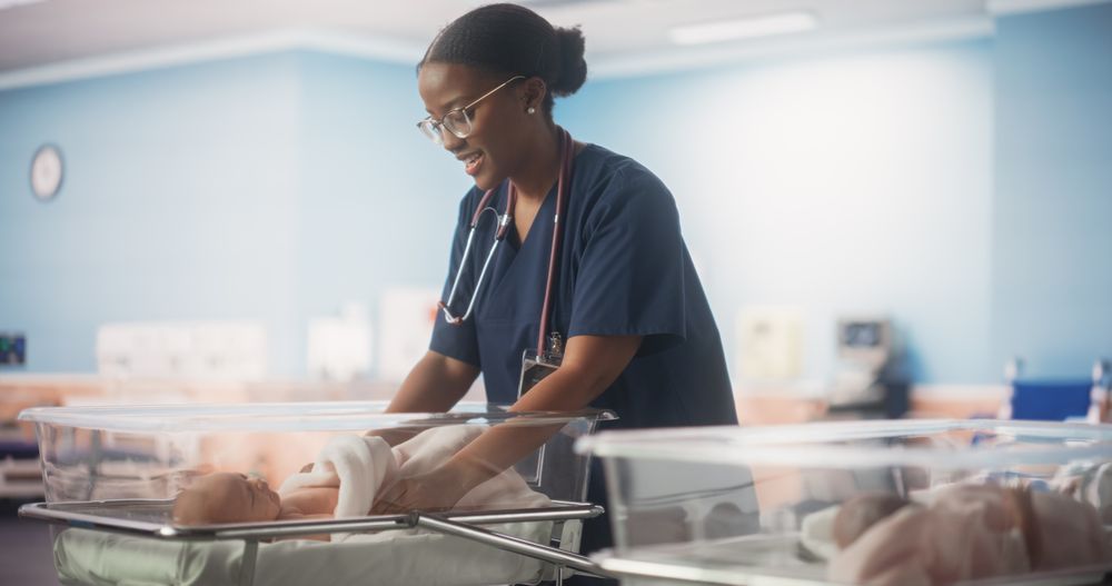 Young Black Pediatrician Taking Care of the Baby and Fixing the Blanket.