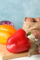 Vegetables, board and knife on wooden background, close up