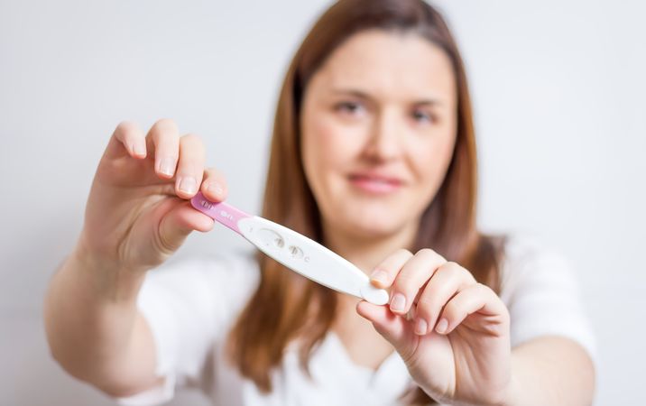 Happy woman showing her positive pregnancy test