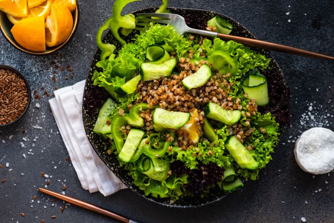Top view of green fresh salad with buckwheat on concrete background served with flax seed and lemon