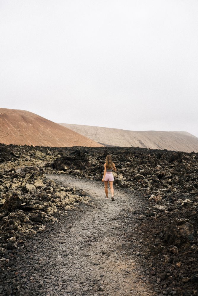 Back of female in shorts walking through volcanic terrain in Lanzarote