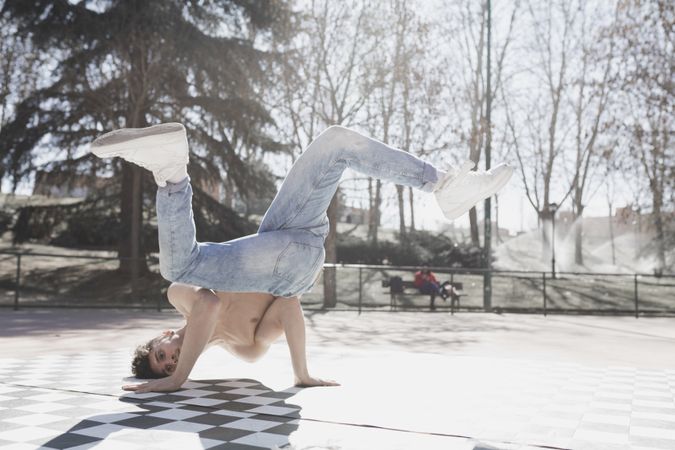 Shirtless man dancing break dance in park