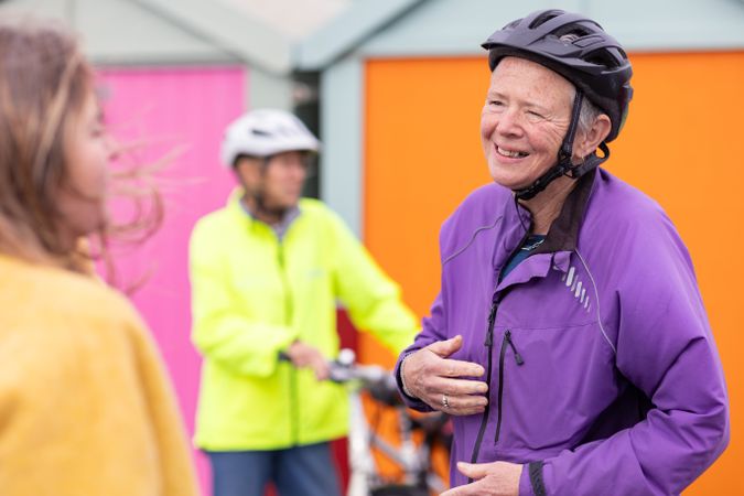 Older female cyclist in helmet chatting outside