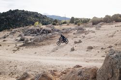 Motorcyclist on off-road track with shrubs and boulders