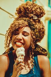 Close up of smiling Black female smiling with an ice cream cone in the sun, vertical