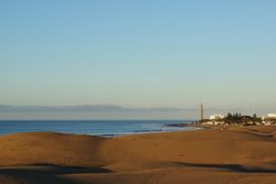Sunny beach at exotic seashore with distant town