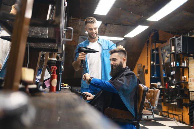 Man looking at watch while having his hair blow dried in salon
