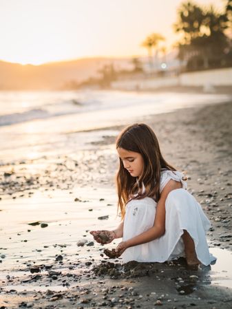 Adorable girl playing with sand on beach