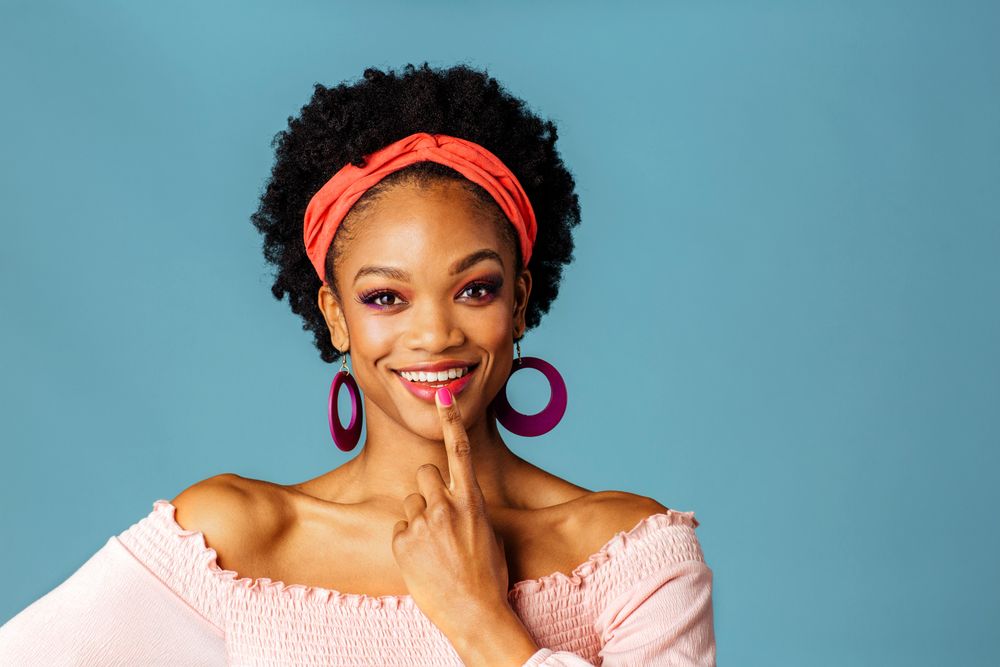 Studio shoot of smiling Black woman with finger on her mouth