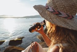Woman relaxing and drinking beer at beach