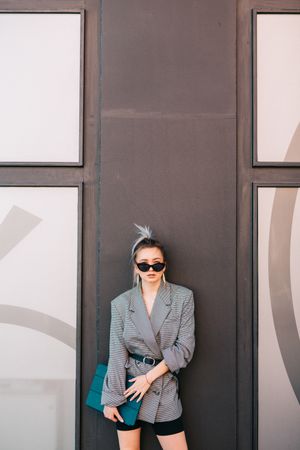 Stylish businesswoman with laptop leaning on wall