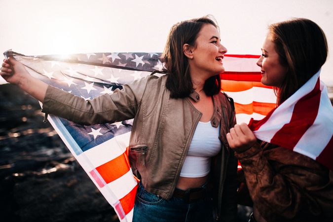 Two young women wrapping themselves themselves in the American flag