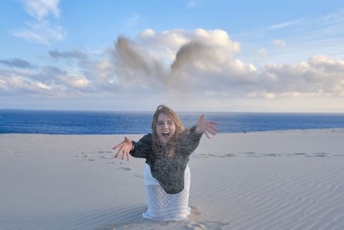 Woman throwing sand on beach
