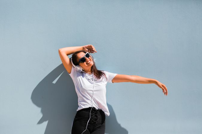 Cheerful casual woman in sunglasses standing on city street