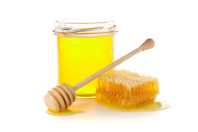 Glass jar, honeycomb and dipper isolated on neutral background
