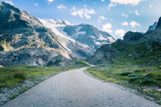 Empty road in rocky valley under cloudy sky
