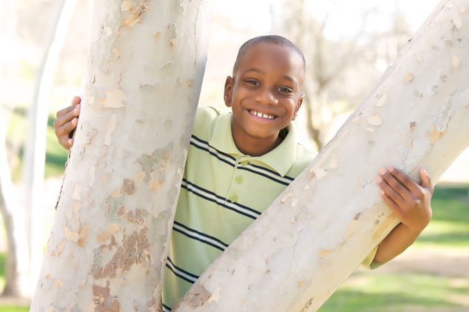 Young Boy Smiling Between Split Tree