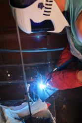 Unrecognizable artisan working on metal in welding workshop