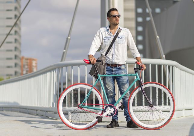 Male with bicycle on city bridge