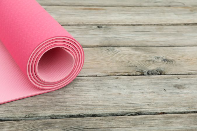 Yoga mat on wooden background, space for text