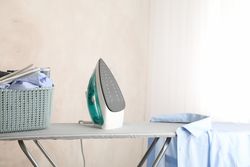 Iron and clean laundry on ironing board, space for text