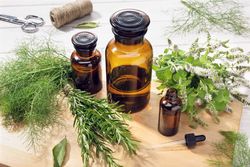 Glass bottles with pipette and herbs scissors threads on table