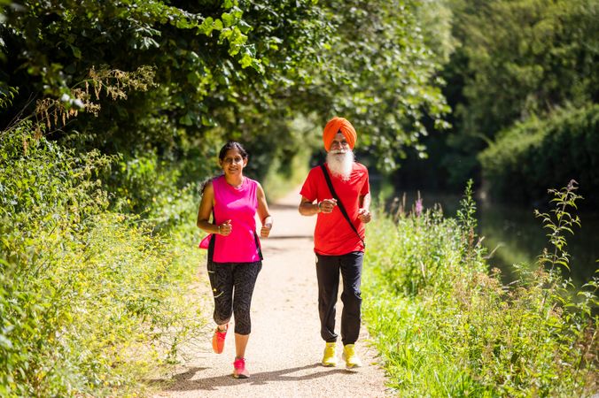 Mature Sikh couple jogging through park