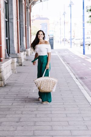 Young happy trendy woman walking in city against blue door