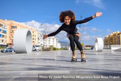 Woman with afro and arms spread roller skating outside bDp2yb