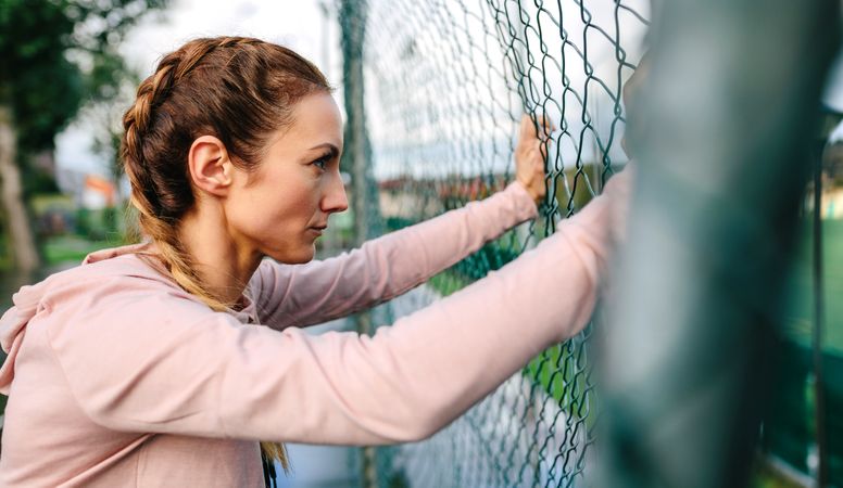 Serious woman with boxer braids leaning on a metal fence