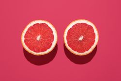 Grapefruit sliced in half minimalist on a magenta background